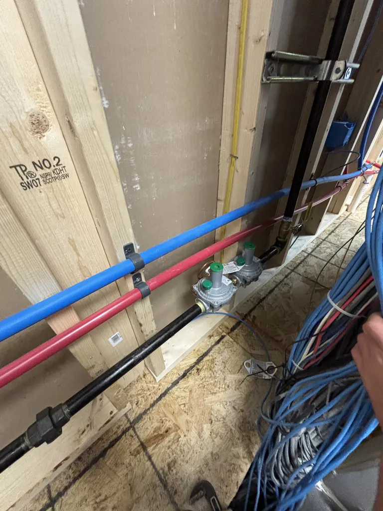 Water and gas lines run through the framing of a new home by Hughes and Sons Gas
