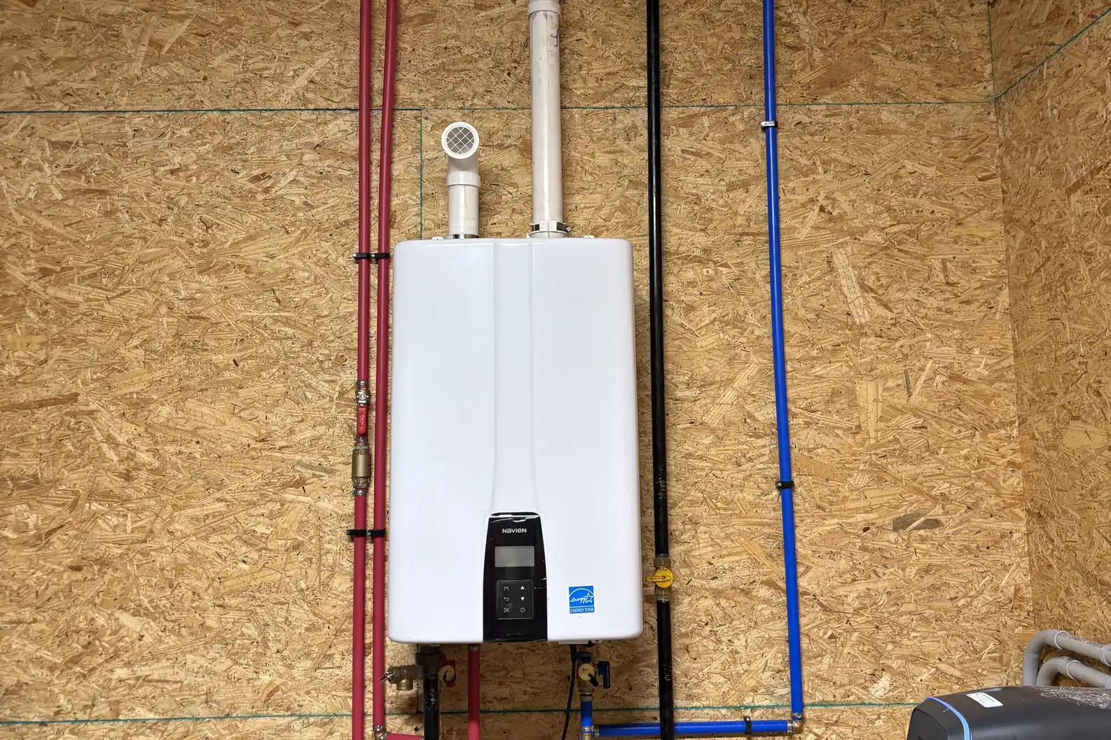 New tankless water heater installed on a wall with gas and water lines